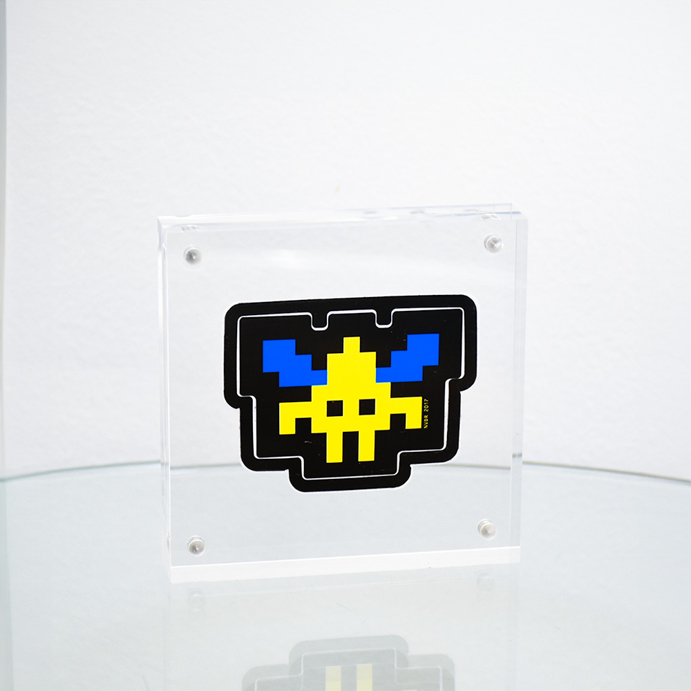 invader yellow and blue sticker in clear frame.